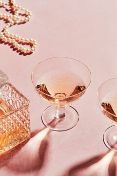 Two Glasses of Aperitif with Decanter on Pink Background
