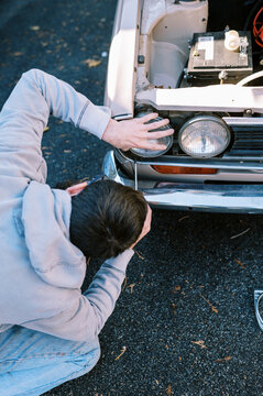 Millennial man replacing headlights in classic station wagon