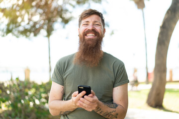 Redhead man with beard sending a message with the mobile