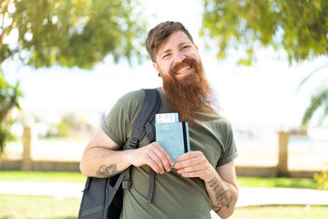 Fototapeta premium Redhead man with beard holding a passport at outdoors