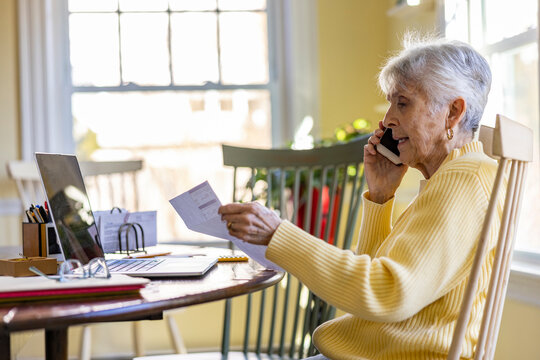 Senior Citizen at Home Paying bills talking to banker 