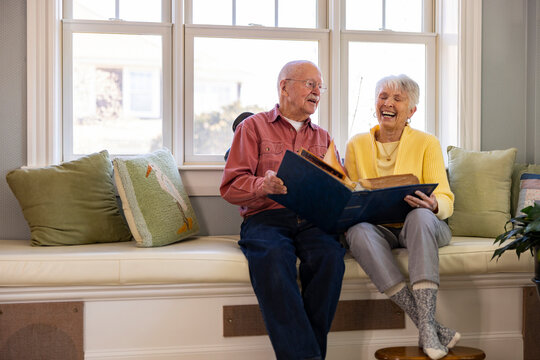 Laughing Senior Citizen couple together at home Looking  photo album 
