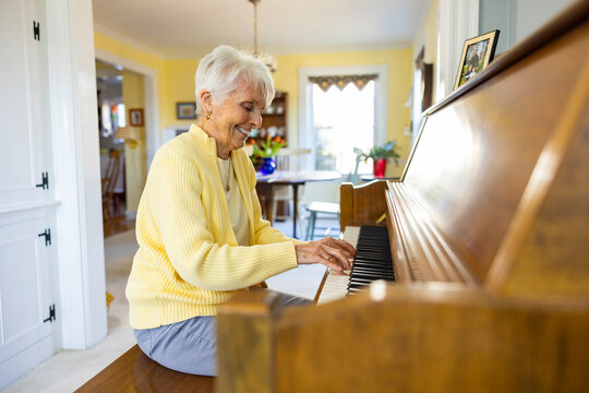 Happy Senior Citizen woman at Home playing piano keyboard big smile