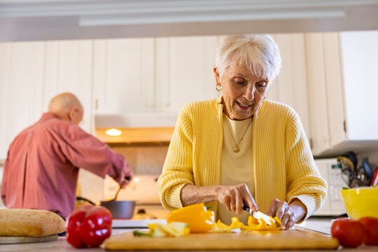 Pretty Senior Citizen couple at home cooking dinner together 