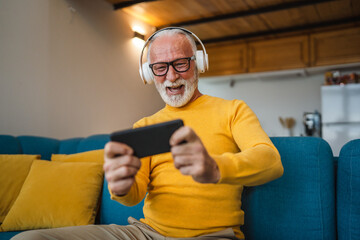 senior old man sit at home play video games on smartphone mobile phone