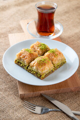 Traditional pistachio baklava with Turkish tea.A plate baklava on burlap sack.Traditional Ramadan dessert