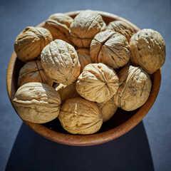 walnuts in a wooden bowl on a dark background