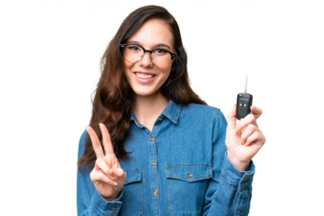 Young caucasian woman holding car keys over isolated background smiling and showing victory sign