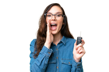 Young caucasian woman holding car keys over isolated background shouting with mouth wide open