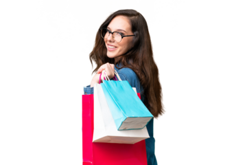 Young caucasian woman over isolated background holding shopping bags and smiling