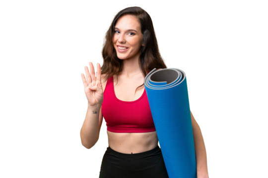 Young sport woman going to yoga classes while holding a mat over isolated background happy and counting four with fingers
