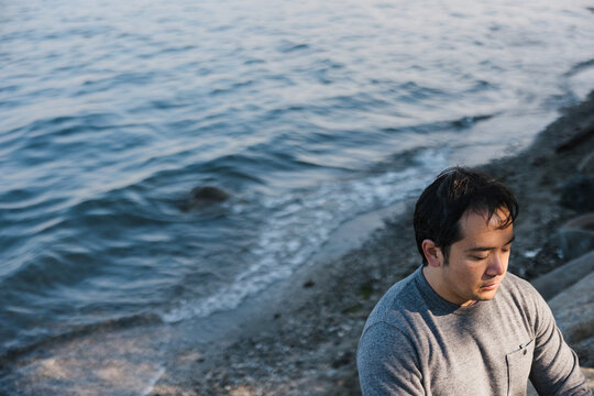 Mindful man meditiating outside on rocks.