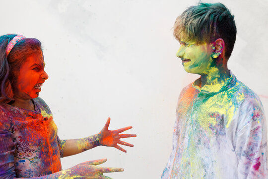 Brother and sister playing holi together with color powder