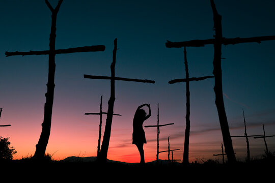Female silhouette dancing between trees with cross shape