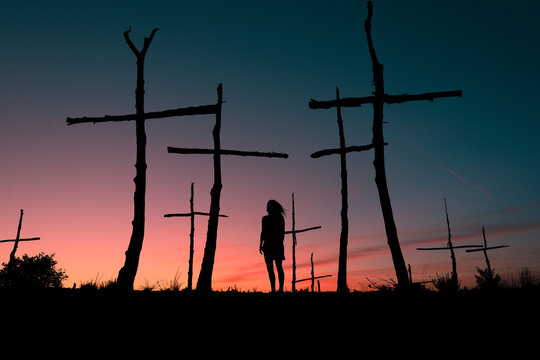 Lonely woman standing in trees field resembling cemetery 