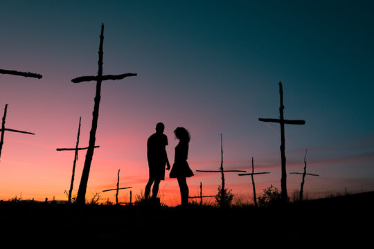 Standing human silhouettes at surreal field of crosses