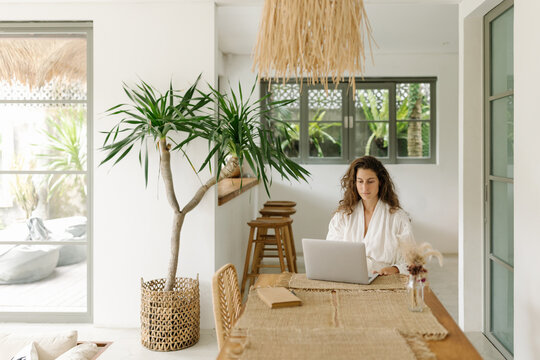 Portrait of young woman at home using laptop