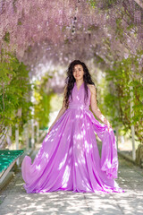 Obraz na płótnie Canvas Woman wisteria lilac dress. Thoughtful happy mature woman in pur