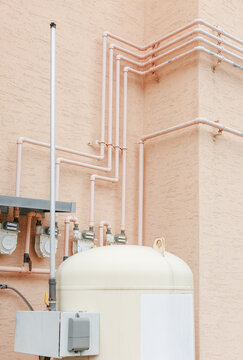Gas pipeline and storage tank installed on pink wall.