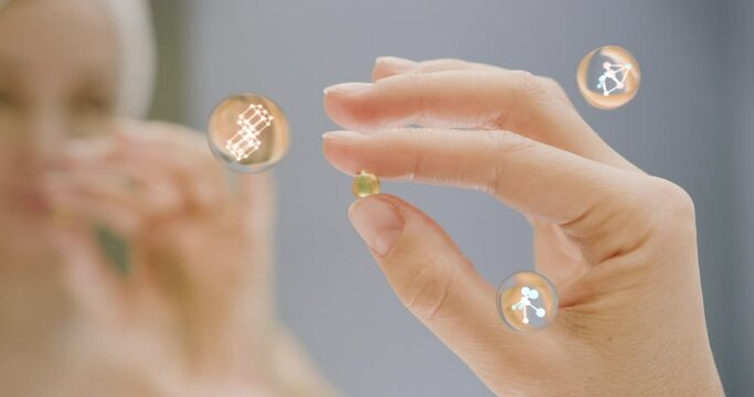Woman fingers holding golden pill which consist from different elements. Medicine pill with animation.