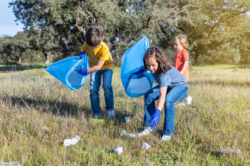 Little Children Picking Up Trash In The Field. Concept Of Caring For The Environment.