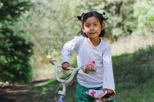 Girl using a bicycle and looking at the camera.