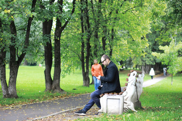 Fototapeta premium A young man in glasses walks in the park with an umbrella during the rain.