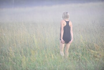A woman walks in the field and looks at the beautiful morning mist