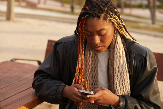Female sitting outdoors sending text message