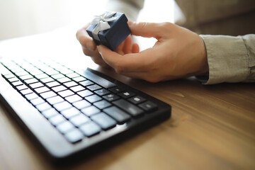 A man with a gift in his hand sits in front of the monitor screen. Order a gift for home and office.