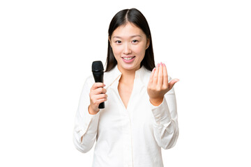 Fototapeta premium Singer picking up a microphone over isolated chroma key background inviting to come with hand. Happy that you came
