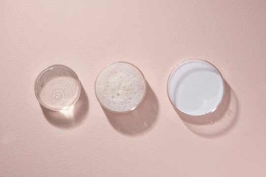 Glass petri dish with different cosmetic products on pastel