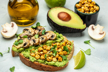 Healthy avocado toasts with chickpeas and mushrooms on a wooden background, vegetarian vegan food. top view. place for text