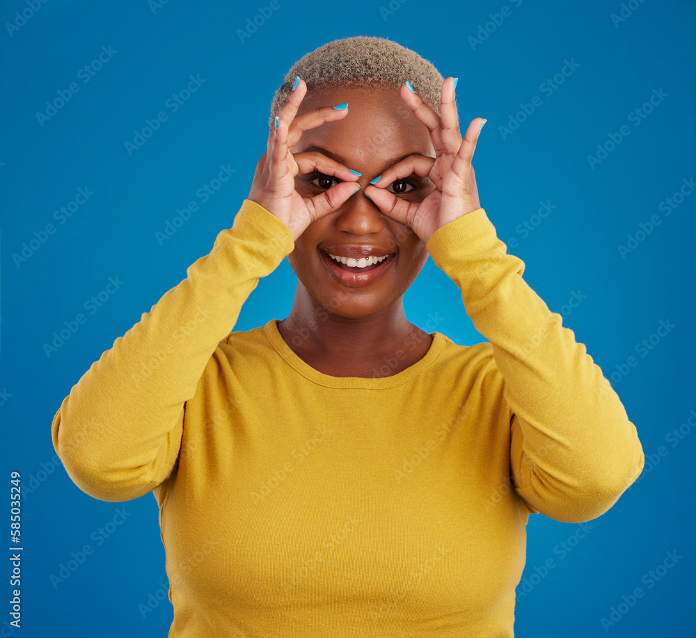 Poster Black woman, binocular hands and eyes in studio portrait for comic funny face with smile, fashion and happy. Student girl, model and ok hand gesture with happiness, youth and pride by blue background