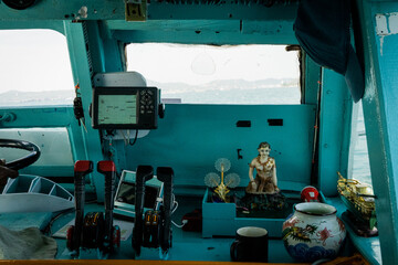 Buddhist ornaments placed on the controls of a boat in Thailand