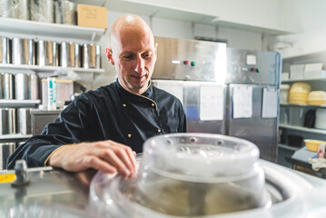 Man professional controlling dairy inside a pasteurizer in a production kitchen. High quality photo