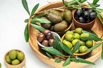 Mixed types of olive in the bowls and olive oil on a light background, banner, menu, recipe place for text, top view