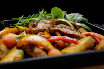 Tender veal with roasted vegetables on black skillet