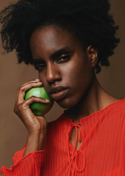 African American Woman holding a green apple near the face