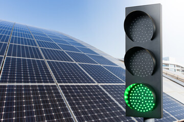 Green traffic light on a background of solar panels. Symbol of sustainable energy and development