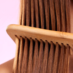Beauty, comb and wood with hair of woman for health, salon and close up in studio. Wellness, keratin and natural bamboo brush with female model for cosmetics, self care and shine on pink background - obrazy, fototapety, plakaty
