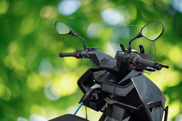 Electric scooter with connected charging cable on a green background
