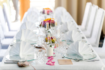 feierlich gedeckter Hochzeitstisch im Restaurant mit Stuhlhussen bei einer Hochzeitsfeier