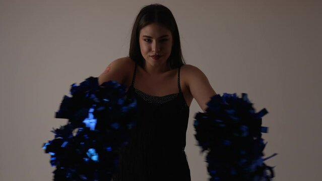 Caucasian young woman dancing with cheerleading pom poms above her head. High quality 4k footage