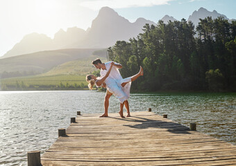 Love, lake and couple dancing together on the pier while on a romantic vacation, adventure or holiday. Romance, dance and young and and woman on a sidewalk in nature while on a summer weekend trip.