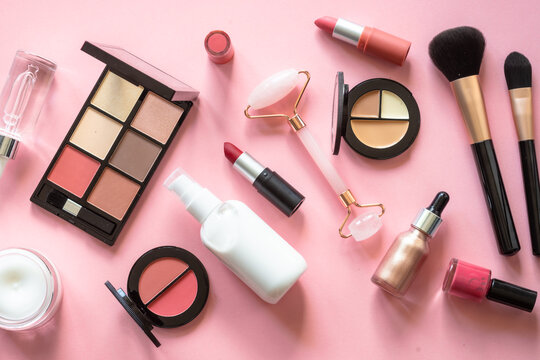 Makeup cosmetic products on pink background. Cream, lipstick, shadow and brushes. Flat lay image with copy space.