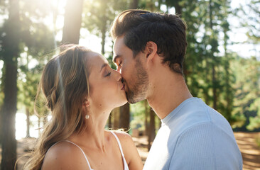 Couple kiss in forest, love and summer with freedom and adventure, affection in relationship and care outdoor. People together in nature park, commitment and trust with romance, content and sunshine