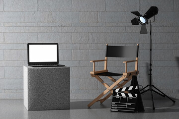 Modern Laptop with Blank Screen near Director Chair, Movie Clapper and Spotlight. 3d Rendering
