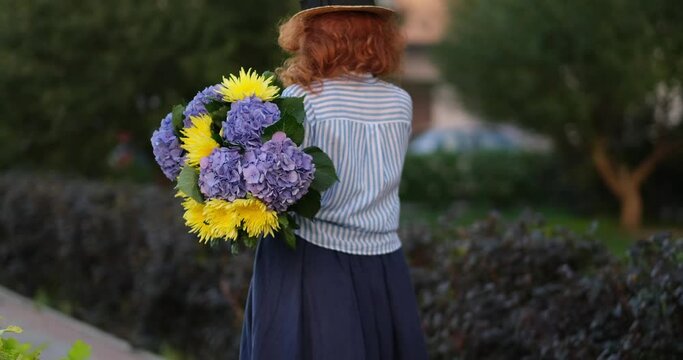 women walking and holding a bouquet of blue hydrangea on the background of green garden , spring concept. High quality photo 4k footage