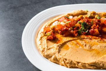 Dish of homemade chickpea hummus with olive oil, paprika, tomato, peppers, parsley, for vegans and vegetarians in a restaurant.